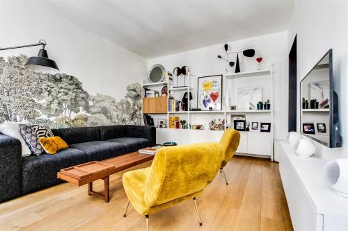 een woonkamer met een bank en een tafel bij Open-plan apartment in the heart of downtown in Neuilly-sur-Seine