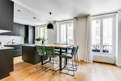 een keuken met een houten tafel en groene stoelen bij Open-plan apartment in the heart of downtown in Neuilly-sur-Seine