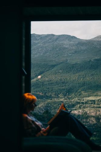 a person sitting in a window looking out at a valley at Skarsnuten Mountain Resort & SPA in Hemsedal