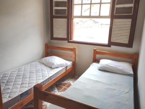 two beds in a room with a window at Casa perto de tudo, pra você ter ótima experiência. Bora Conhecer Ouro Preto.... in Ouro Preto