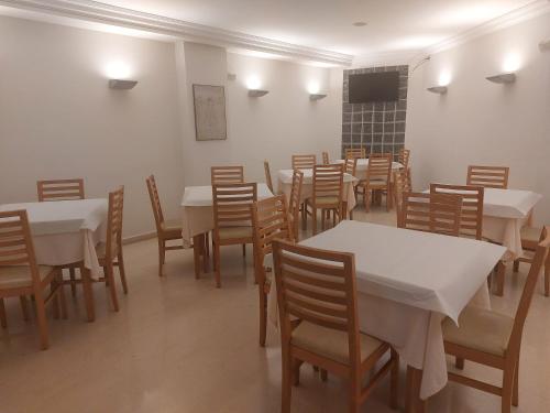 uma sala de jantar com mesas brancas e cadeiras de madeira em U Hotel Ogalia Vigo em Vigo