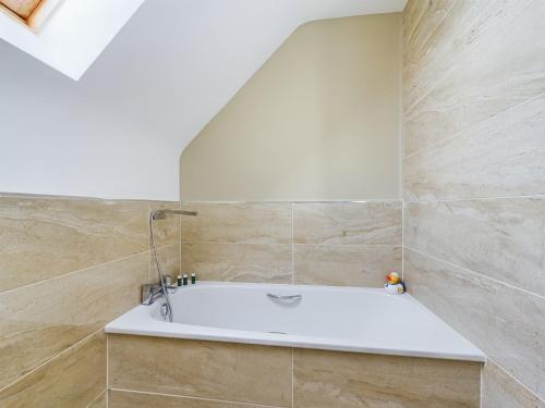 a white bath tub in a bathroom with tiles at Mourne Mountain Bliss, Rostrevor 4BR Cottage with Patio & BBQ ideal for a relaxing getaway in Rostrevor
