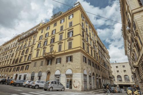 un gran edificio amarillo con coches estacionados frente a él en Mirabilia House Termini en Roma