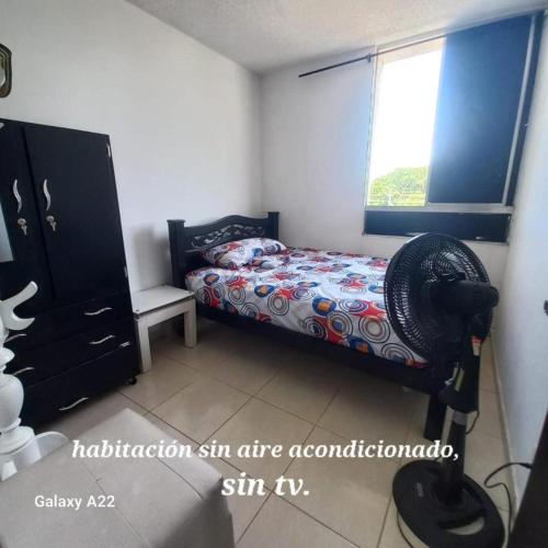 APARTAMENTO AMOBLADO - SIN AIRE ACONDICIONADO في فاليدوبار: غرفة نوم بسرير ونافذة ومروحة