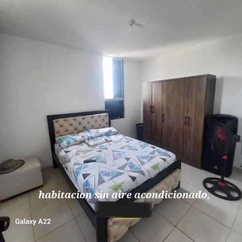 a bedroom with a bed and a wooden cabinet at APARTAMENTO AMOBLADO - SIN AIRE ACONDICIONADO in Valledupar