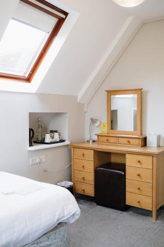 a bedroom with a bed and a dresser with a mirror at Red Mullions Guest House in Oxford