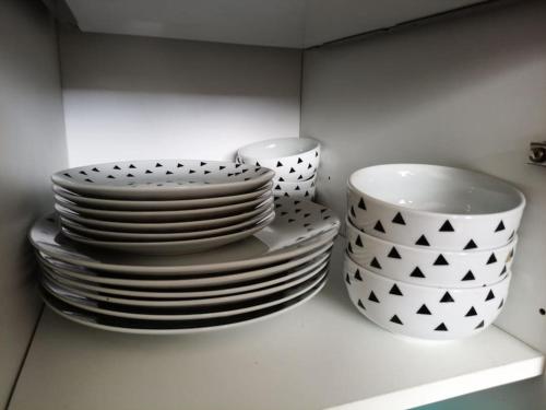 a pile of plates and bowls sitting on a shelf at Appartement avec belle vue sur montagne in Égat
