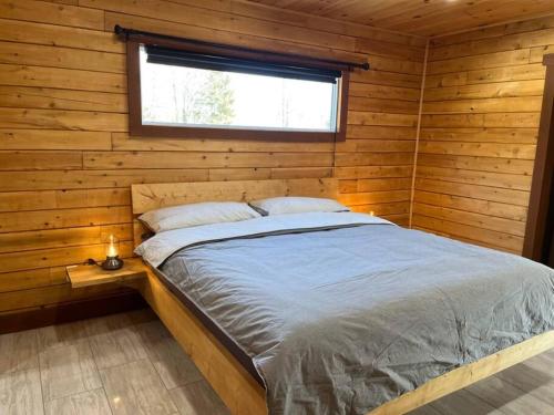 een bed in een houten kamer met een raam bij Geese Villa Log House in Harrington