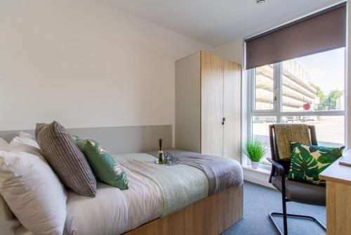 Schlafzimmer mit einem Bett, einem Schreibtisch und einem Fenster in der Unterkunft Exquisite Ensuites at The Croft Derby in Derby