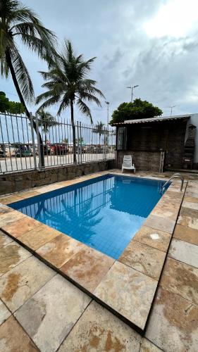 a blue swimming pool with a fence and palm trees at Sonho de Iracema Hostel Boutique in Fortaleza