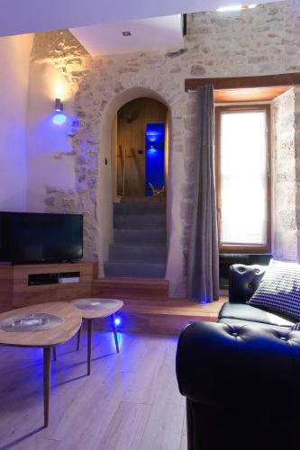 a living room with a couch and a tv and stairs at Logis de Cupidon in Châteauneuf-du-Rhône