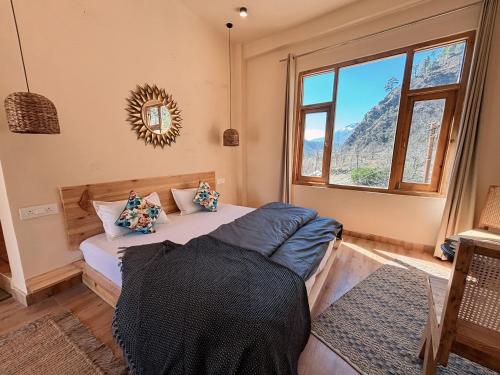 a bedroom with a bed and a window at Grham Hostel Kasol, Katagla in Kasol