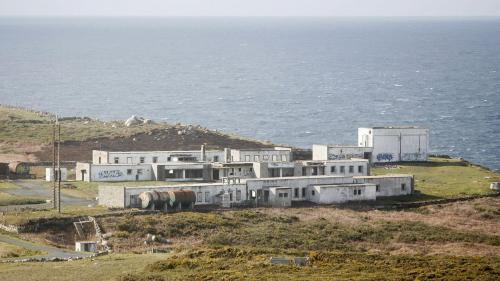 a building on top of a hill next to the ocean at Cabañas O Recuncho do Sor in O Barqueiro