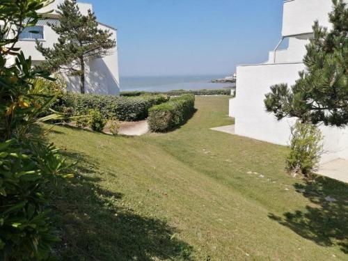 une cour herbeuse à côté d'un bâtiment blanc dans l'établissement Studio COSY Front de Mer, à Royan