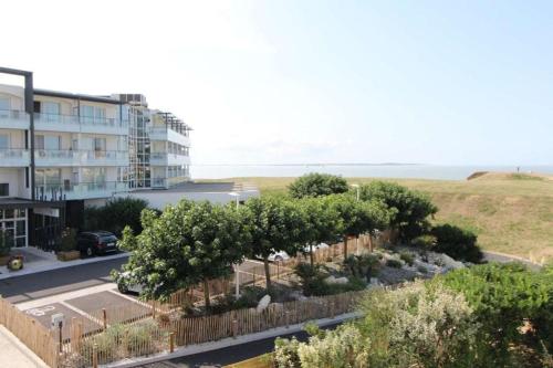 - une vue sur un bâtiment et un parking arboré dans l'établissement Studio COSY Front de Mer, à Royan