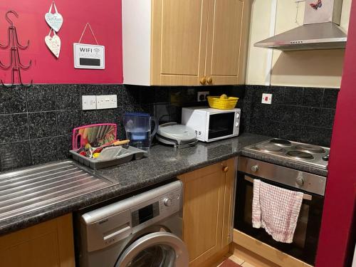 a kitchen with a washing machine and a microwave at Hastings street in Luton