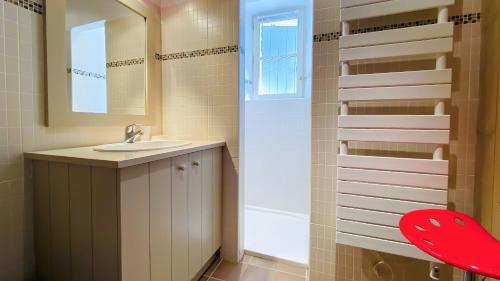 La salle de bains est pourvue d'un lavabo et d'une chaise rouge. dans l'établissement Charmante maison de village, au Bois-Plage-en-Ré