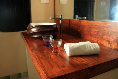 a wooden counter with two glasses and a towel at Casa de Sekara Near White Town in Puducherry