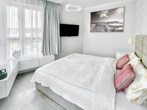 - une chambre blanche avec un lit et une fenêtre dans l'établissement Sandy Apartment Deluxe Horyzont Międzyzdroje, à Międzyzdroje