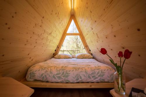 een bed in een houten kamer met een raam bij Baita Eleonora in Argegno