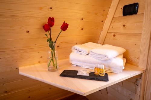 un estante con un jarrón con rosas rojas y toallas en Baita Eleonora en Argegno