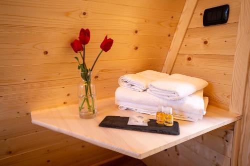 a shelf with a vase with red roses and towels at Baita Eleonora in Argegno