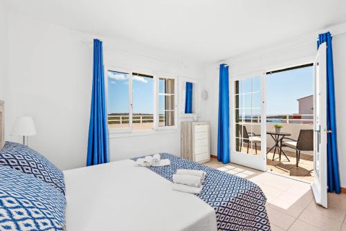 1 dormitorio con cortinas azules, 1 cama y balcón en Villa Cayetana, en Mahón