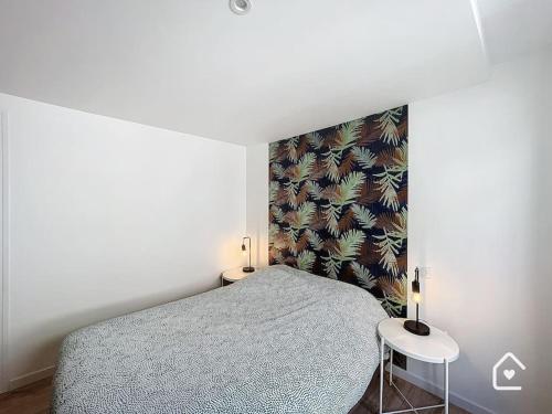 ein Schlafzimmer mit einem Bett, zwei Tischen und einer Wand in der Unterkunft Bienvenue chez Janna - 6 Personnes - Parking facile in Châtellerault