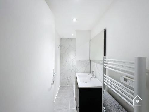 ein weißes Badezimmer mit einem Waschbecken und einem Spiegel in der Unterkunft Bienvenue chez Janna - 6 Personnes - Parking facile in Châtellerault