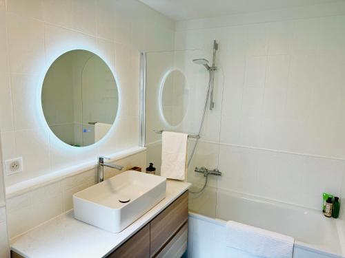 a white bathroom with a sink and a mirror at Penthouse over Monaco in Beausoleil