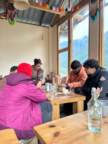a group of people sitting around a wooden table at Grham Hostel Kasol, Katagla in Kasol