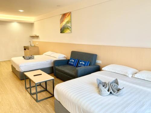 a hotel room with two beds and a chair at Deco Home @ Aru Suites in Kota Kinabalu