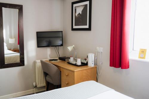 a bedroom with a desk with a bed and a television at Red Mullions Guest House in Oxford
