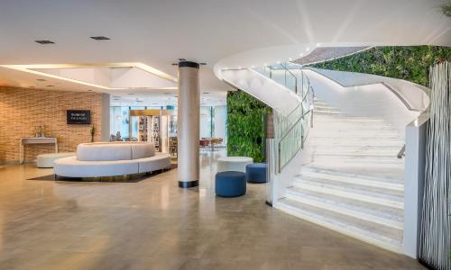 a lobby with a staircase and a couch at Occidental Murcia Agalia in Murcia