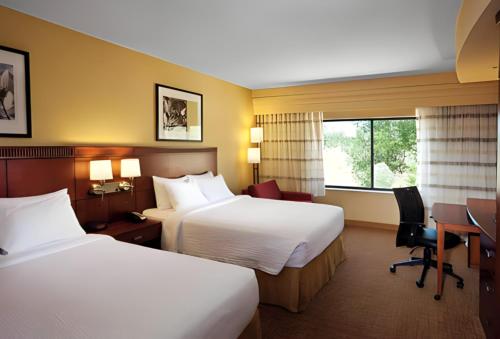 a hotel room with two beds and a desk at Courtyard Missoula in Missoula