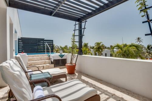 un patio con sillas blancas y mesas en un balcón en Las Terrazas Resort en San Pedro