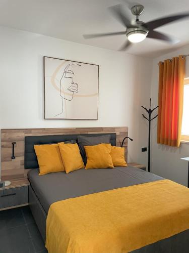 a bedroom with a bed with yellow pillows and a ceiling fan at Valkane Beach Apartments in Pula