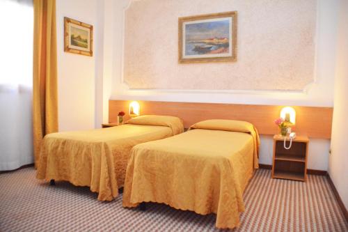 a hotel room with two beds with yellow sheets at Hotel Delta Florence in Calenzano