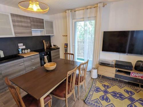 Il comprend une cuisine avec une table en bois, des chaises et une télévision. dans l'établissement Logement chaleureux aux portes de Paris, à Noisy-le-Sec