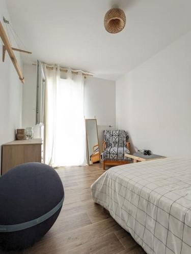 une chambre blanche avec un lit et une chaise dans l'établissement Logement chaleureux aux portes de Paris, à Noisy-le-Sec