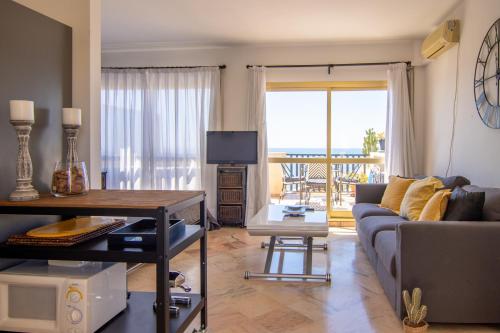 ein Wohnzimmer mit einem Sofa und einem Tisch sowie einem Balkon in der Unterkunft OleHolidays 655 Romana Playa vistas al mar in Marbella
