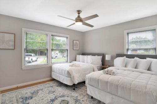 ein Schlafzimmer mit zwei Betten und zwei Fenstern in der Unterkunft Centrally Located Midtown Cottage-HistoricDistrict in Mobile