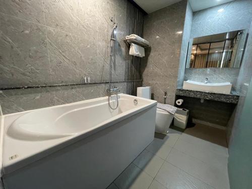La salle de bains est pourvue d'une grande baignoire blanche et d'un lavabo. dans l'établissement Bangkok City Link Hotel, à Bangkok