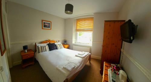 a small bedroom with a bed and a television at The Shrubbery Hotel in Shepton Mallet