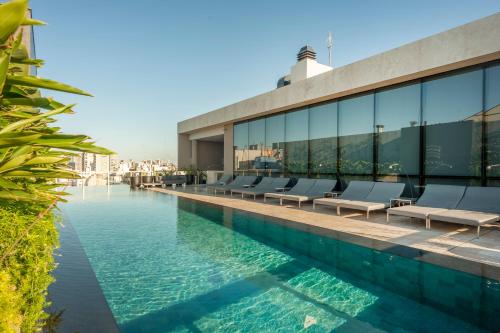 Una piscina con tumbonas al lado de un edificio. en Viví y Disfrutá el Lujo en Torre Decó Recoleta Armani powered by Argenhost -902-, en Buenos Aires