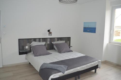 une chambre avec un grand lit dans une pièce blanche dans l'établissement Gîte de LANVIAN, à Guissény