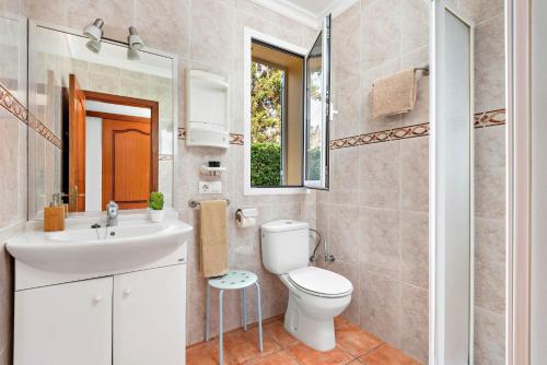 uma casa de banho com um WC, um lavatório e um espelho. em Villa Sol Menorca em Punta Prima