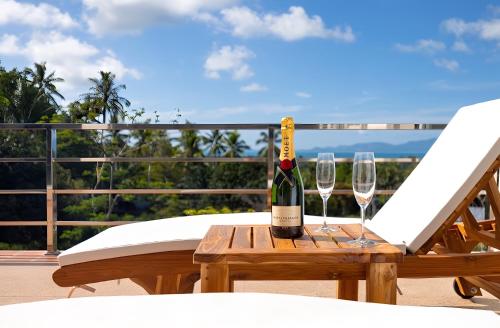 a bottle of wine sitting on a table with two glasses at Blue Elephant Villa Koh Phangan in Haad Pleayleam