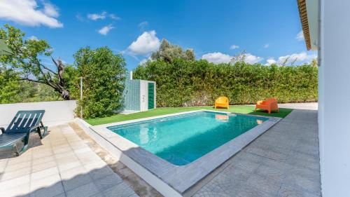 a swimming pool with two chairs next to a yard at Sunny & Calm 4 BDR House W/ Pool by Lovelystay in Santo Estêvão