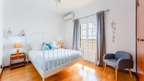 a bedroom with a bed and a chair and a window at Sunny & Calm 4 BDR House W/ Pool by Lovelystay in Santo Estêvão